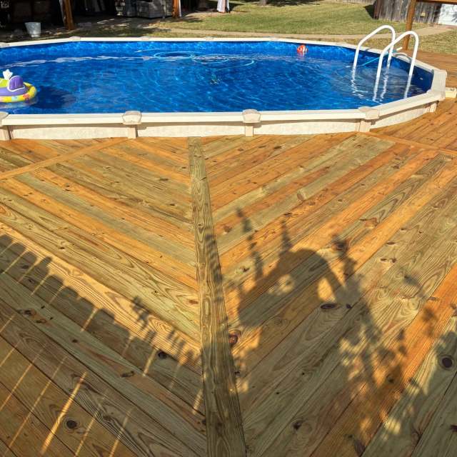 Angled deck boards meeting at a center board beside an above-ground pool