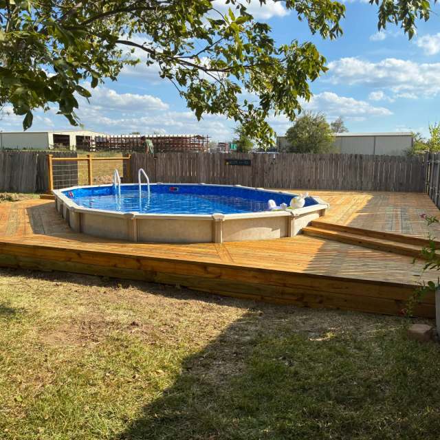 Finished pressure treated pool deck wrapping around an above-ground pool in Mabank, TX