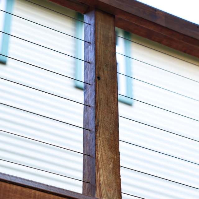 Stainless cable railing runs tensioned between stained wood deck posts