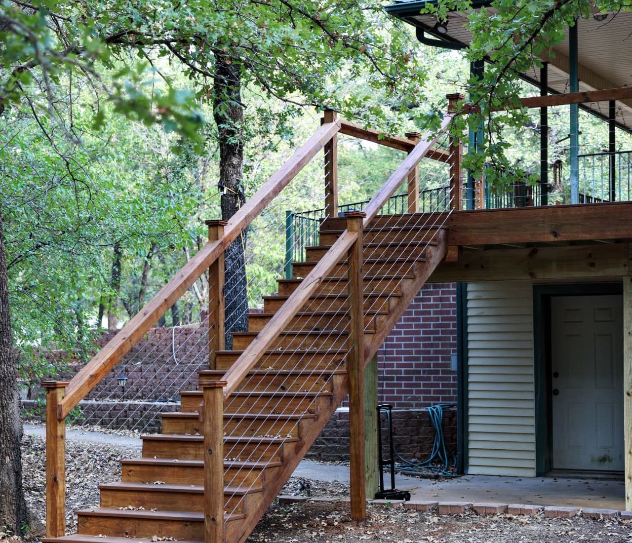 Stained wood stair run with cable railing leading down to grade